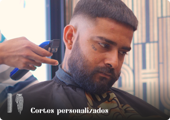 Primer plano de un barbero perfilando la barba de un cliente con precisión, ilustrando el servicio de cortes personalizados y atención al detalle.